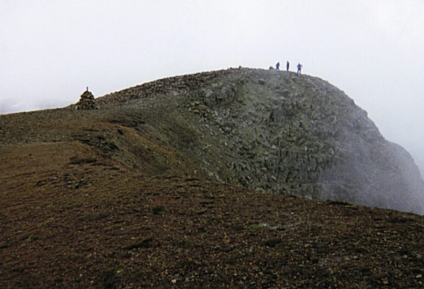 Hikers on the summit of Mount Sopris with the memorial visible at center-left.