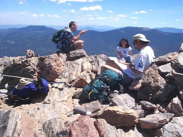 Tommy reading the summit register while sharing the summit with two other people (Marshal and ???).  Note that you can see Pikes Peak in the background (when looking south).