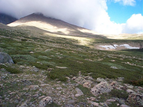 The trail traverses up this meadow (from lower left to upper right) and the high winds begin above the saddle (right).