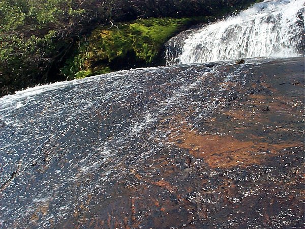 A closer shot showing the water glistening over a smooth rock.