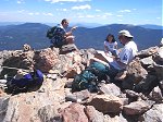 Tommy reading the summit register while sharing the summit with two other people (Marshal and ???).  Note that you can see Pikes Peak in the background (when looking south).