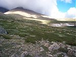 The trail traverses up this meadow (from lower left to upper right) and the high winds begin above the saddle (right). The trail traverses up this meadow (from lower left to upper right) and the high winds begin above the saddle (right).