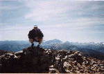 Crouching on the summit of Mount Sopris with Capital Peak on the horizon